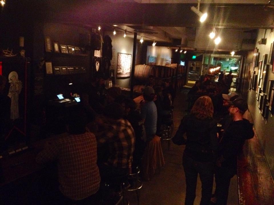 A group of people gathered in a dark room, at a brewery bar
