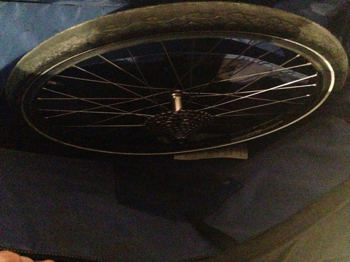Downward view of a rear bike wheel with cassette, on top of a bike carrier bag