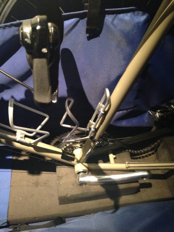 Cropped, downward view of the frame with crankset, of a tan Surly Long Haul Trucker bike, packed into a bike carrier bag