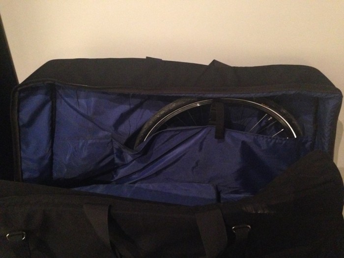 A bike wheel, packed in the wheel pocket of a bike carrier bag
