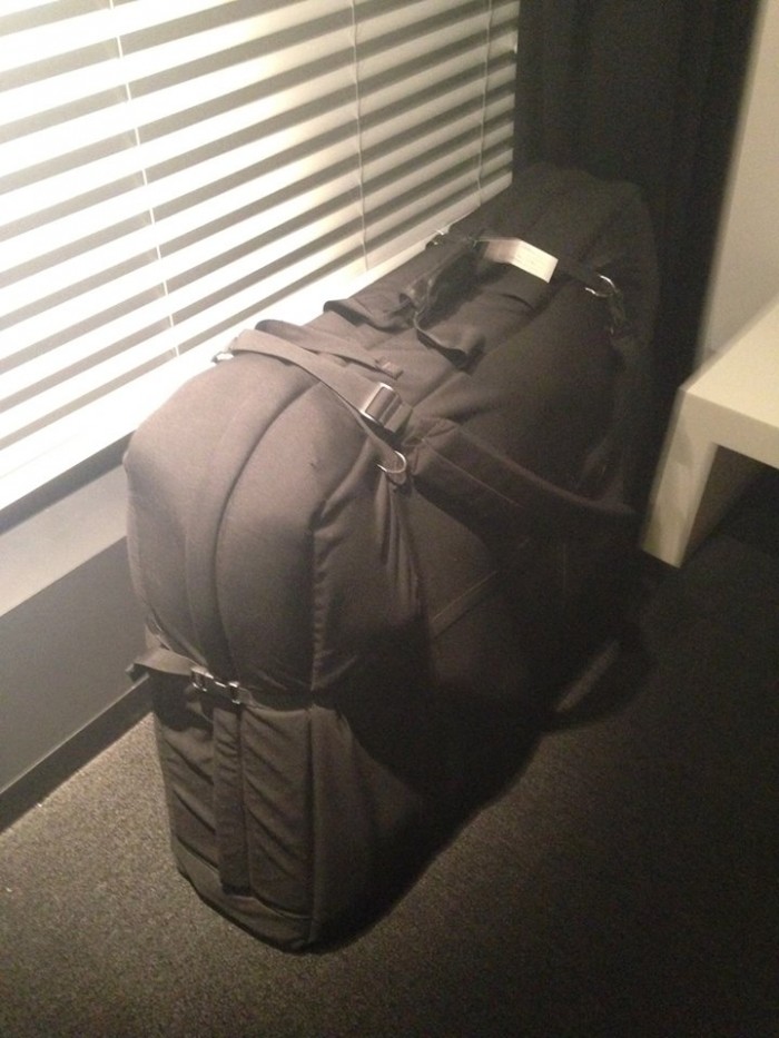 Downward view of an upright, fully loaded, black bike carrier bag