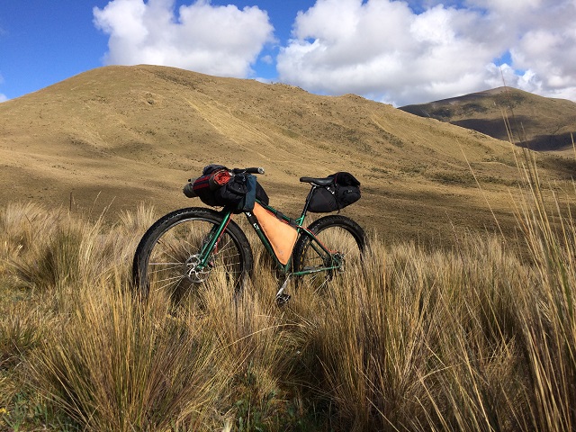 Front left side view of a Surly Krampus bike, parked in tall prairie grass, with brown, grassy hills in the background