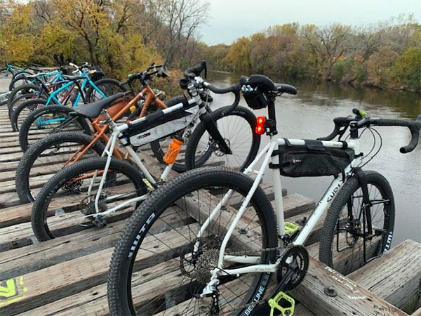 Several Surly bikes parked on railroad bridge over river, tires in between ties holding them upright