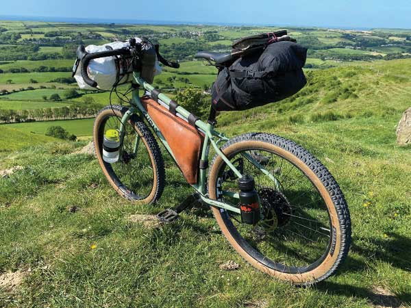 Surly Ghost Grappler loaded for bikepacking on hill overlooking contryside