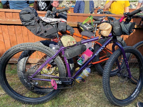 Purple Surly Krampus parked outside pub with bikepacking bags in front of other loaded bikes