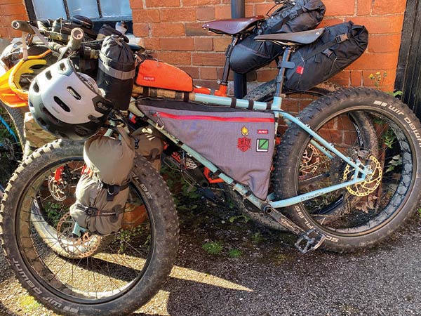 Surly Wednesday loaded to the max with bikepacking bags and gear parked in front of other loaded bikes