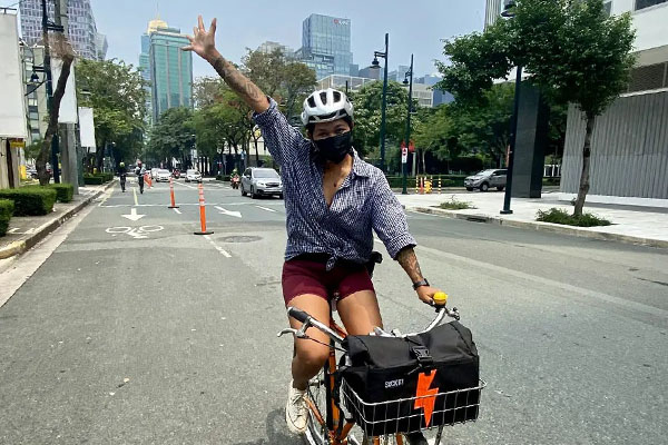 Aneka riding one handed on city street, hand in air wearing helmet and mask
