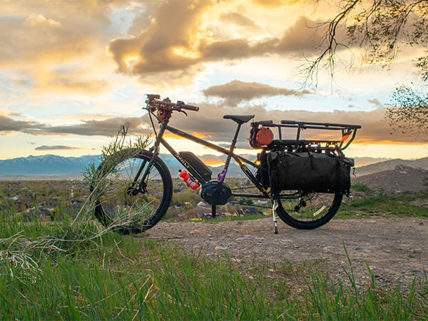 Big Easy parked outside on hilltop, side view with kickstand down, mountains in distance at sunset