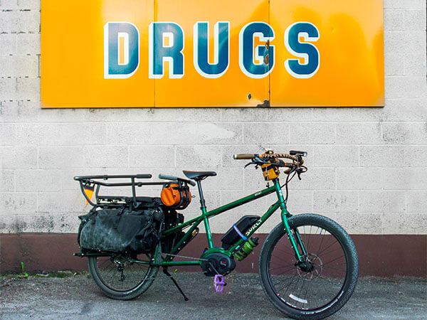 Surly Big Easy with front rack and bag, Kid Corral seat and bars, kickstand down in parcking lot in front of sign, Drugs