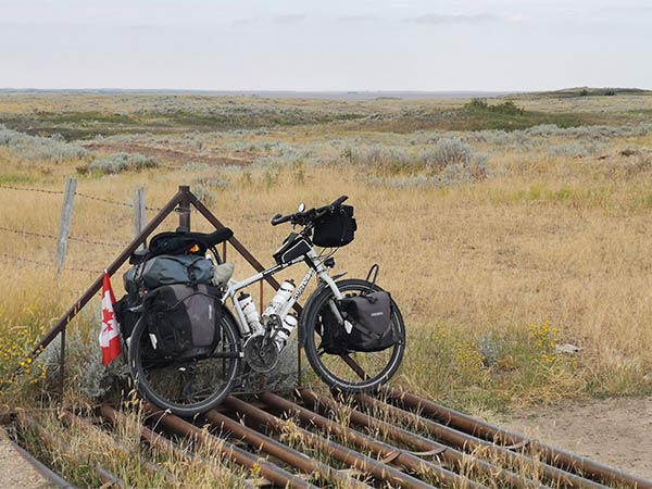 Loaded Troll bike parked against cattle grate and barbed wire fence in high elevation prairie