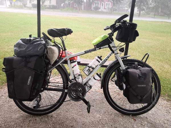 Loaded Troll bike under outdoor shelter during rain shower in neighborhood