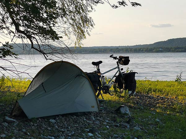 Camp set-up on lake shore, bike parked next to tent