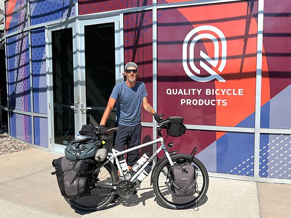 Yann standing with loaded Troll bike in from of Quality Bicycle Products front doors