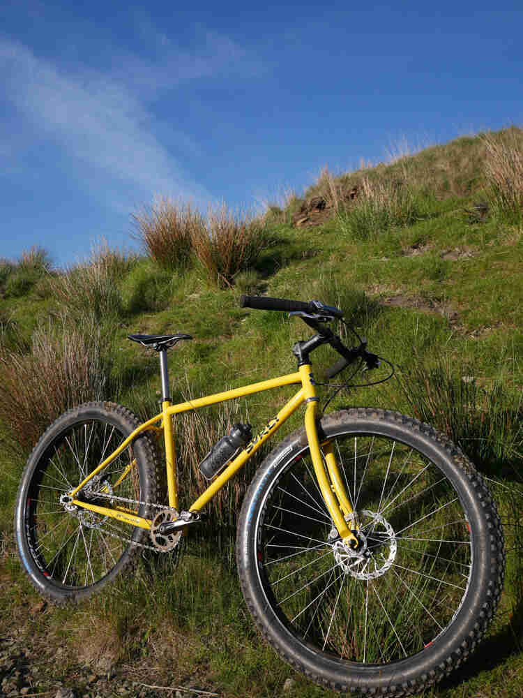 Right side view of a yellow Surly 1x1 bike, parked on a grassy hill