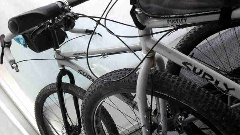 Cropped view of a white Surly Pugsley bike, stacked next to another white Surly bike
