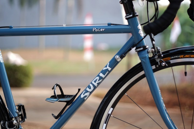 Cropped view of the front half of a blue Surly Pacer bike with a bottle mount on the down tube