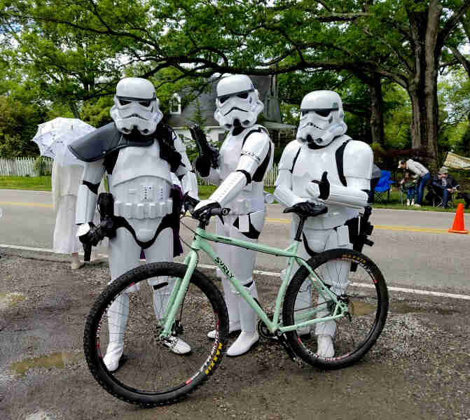 Left side view of mint Surly bike with 3 people, dressed in Star Wars Stormtrooper costumes standing behind