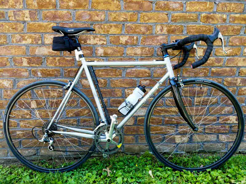 Right profile of a white Surly bike leaning on a brick wall