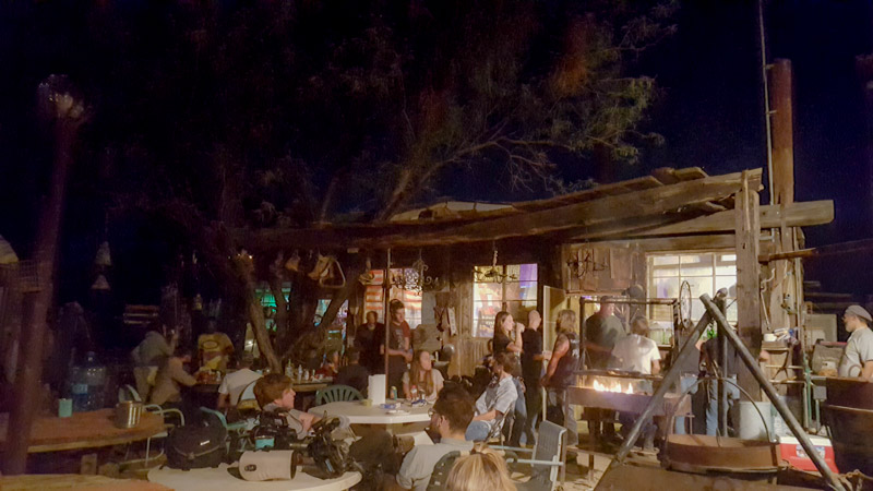 A group of people gathering outside an old wooden saloon at night