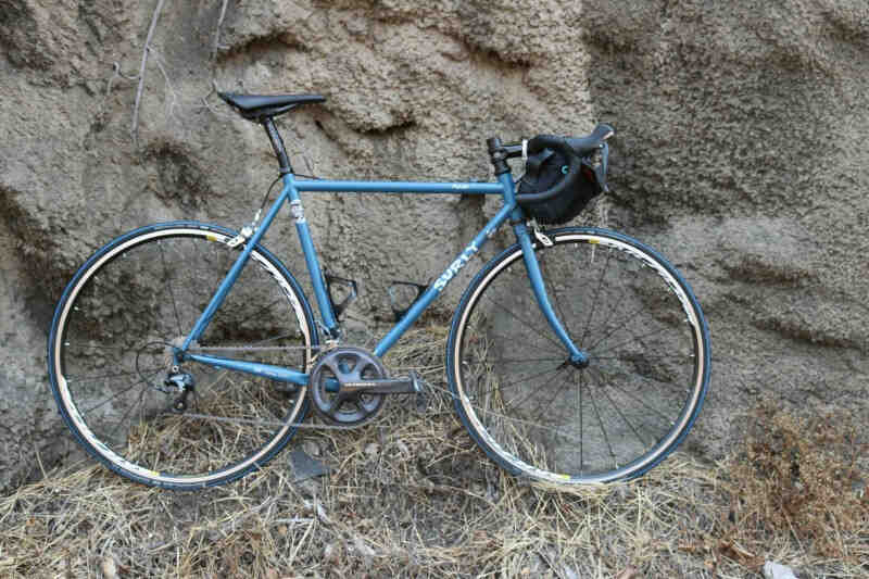 Right side view of a Surly Pacer bike, blue, leaning on a mountain wall