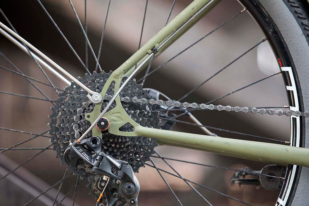 Right side, close up of an olive drab Surly Bridge Club bike, focused on the rear wheel area with components