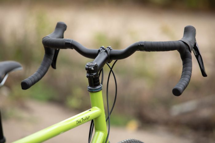 A close up of the front portion of a Surly Disc Trucker bike focused on handlebars and head tube portion of the frame