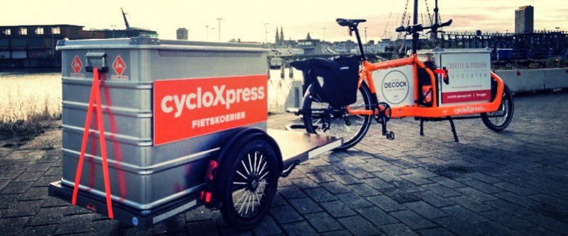 A cycloXpress bike and trailer on a brick platform, with a shipyard in the background