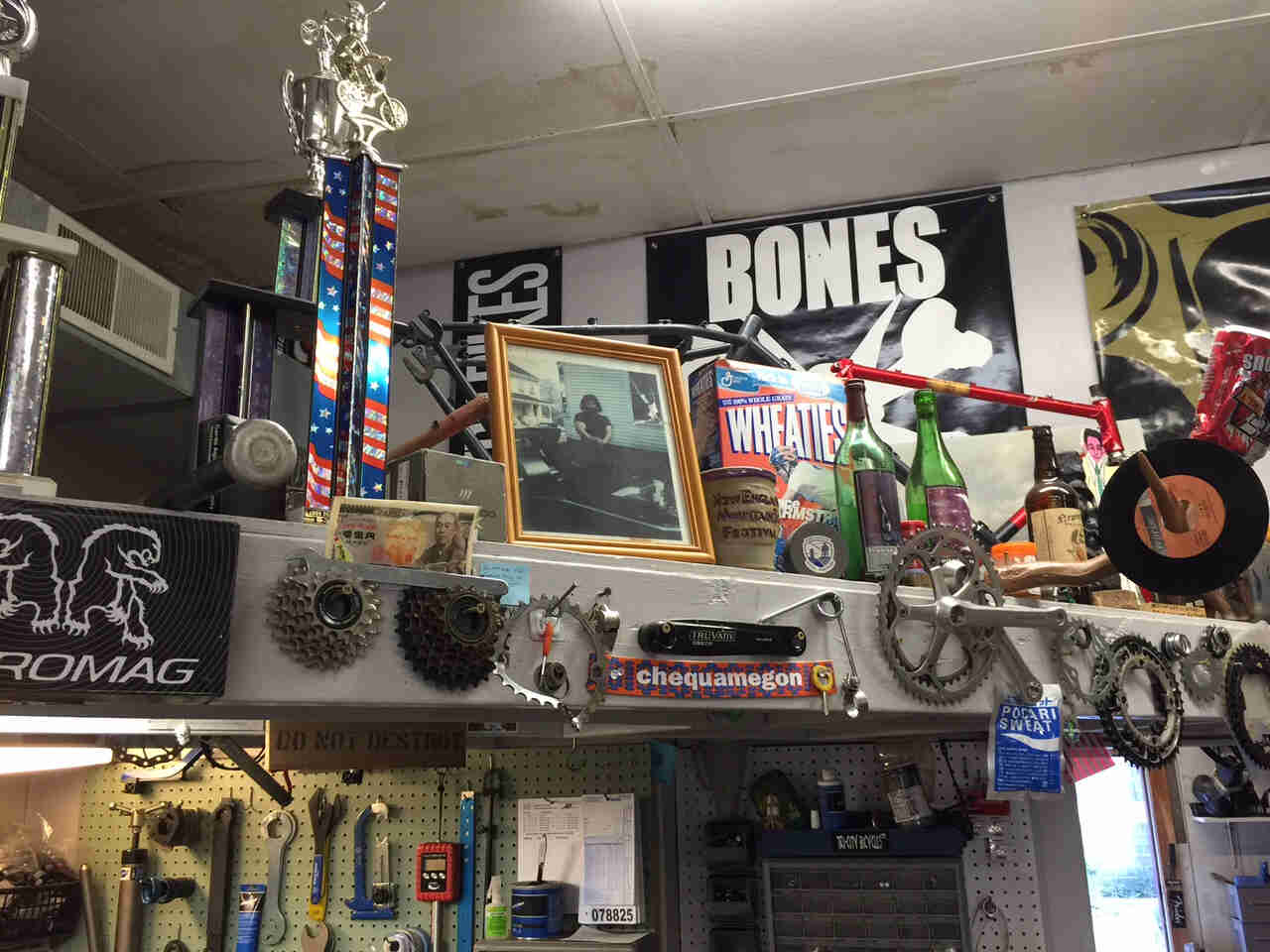 A collection of bike parts, posters and random items, on a shelf and mounted to walls