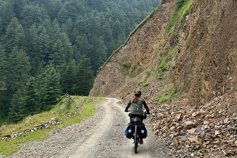 Ashim riding fully loaded touring bike up gravel mountain road