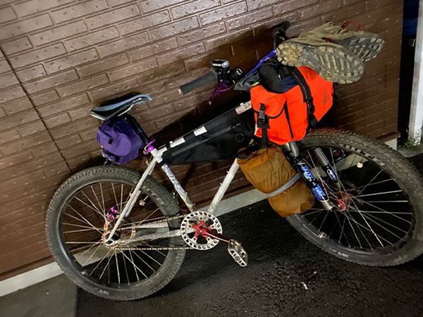 Kaneyan's custom white Surly moutain bike loaded with gear for bikepacking parked against wall