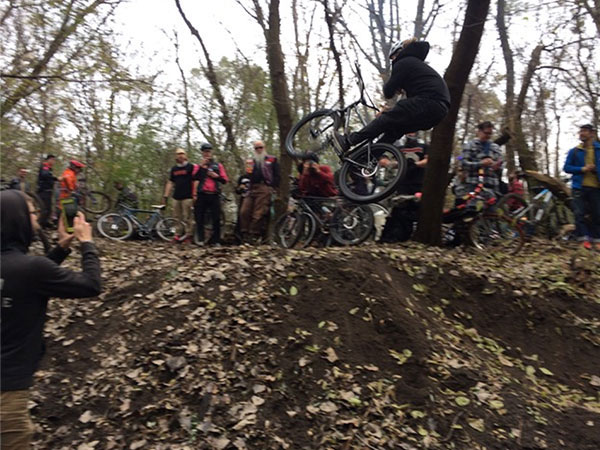 Cyclist in air off dirt jump, spectators watching