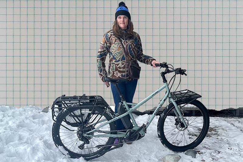 Athena standing outside in snow behind her Surly Skid Loader cargo ebike