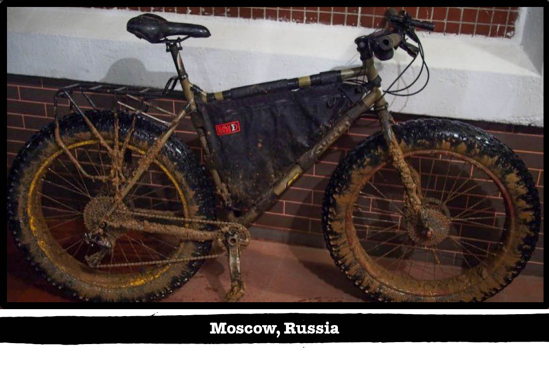 Right side of view of a mud covered Surly fat bike against a red brick wall - Moscow, Russia tag below image