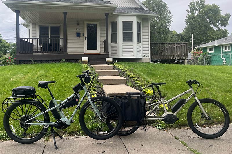 Surly Skid Loader bike and Big Easy bike parked next to eachother in front of house on sidewalk