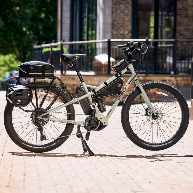 Surly Skid Loader bike parked on sidewalk using  kickstand with frame bag, rack bag, top tube bag , handlebar bag