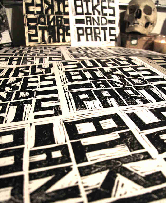 Side view of a table covered with copies of black & white, Surly Bikes catalog cover prints