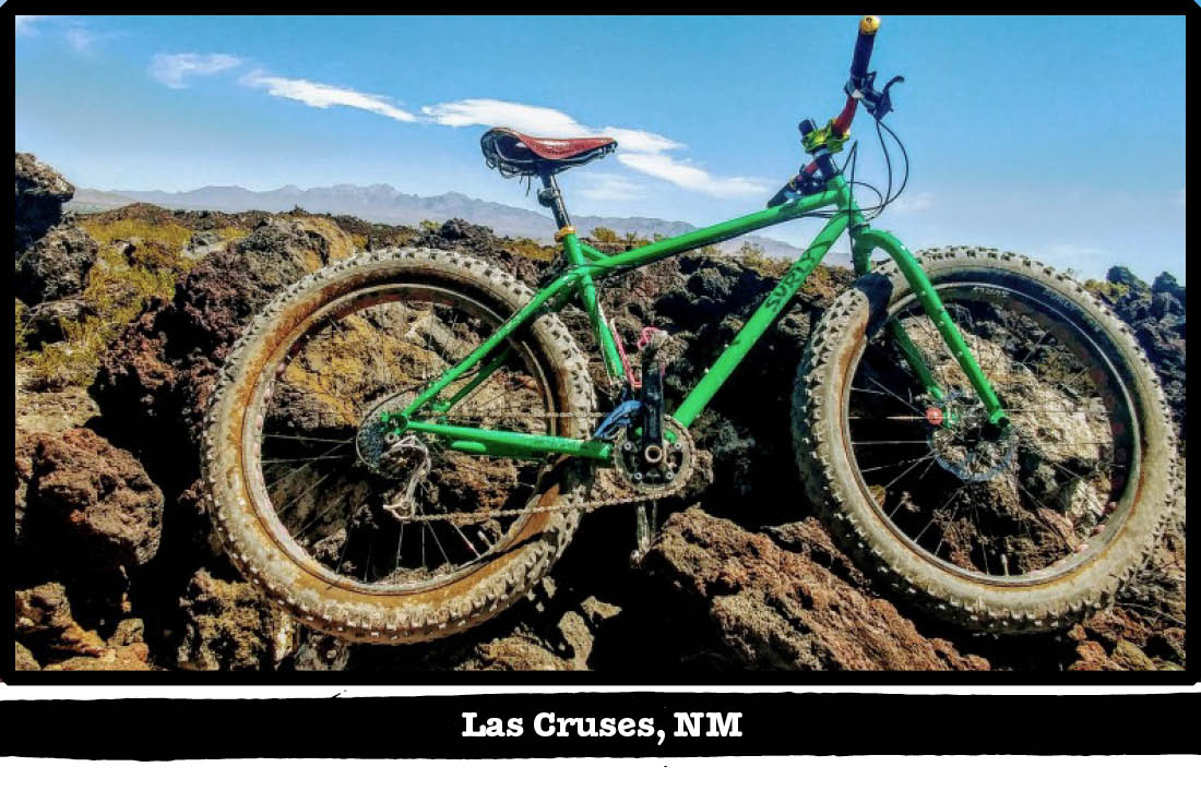 Right profile of a green Surly fat bike in front of a rock ledge - Las Cruses, NM tag below image