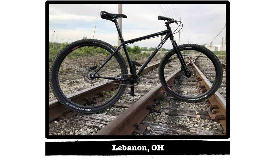 Right profile of a black Surly bike standing across railroad tracks - Lebanon, OH tag below image