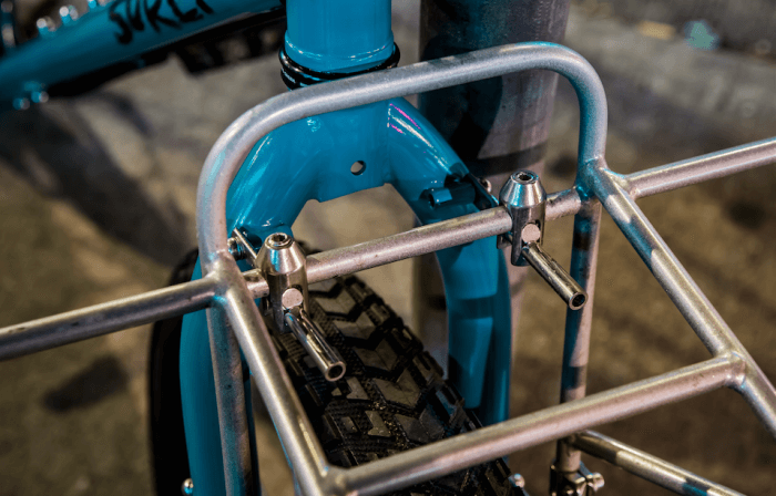 Surly 24-Pack rack - silver - mounted on a turquoise Surly bike - upper fork mount detail - front view