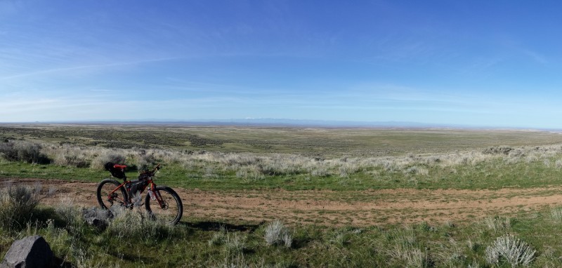 Panoramic image of Surly bike with gear, parked on the side of a dirt road in a plains field