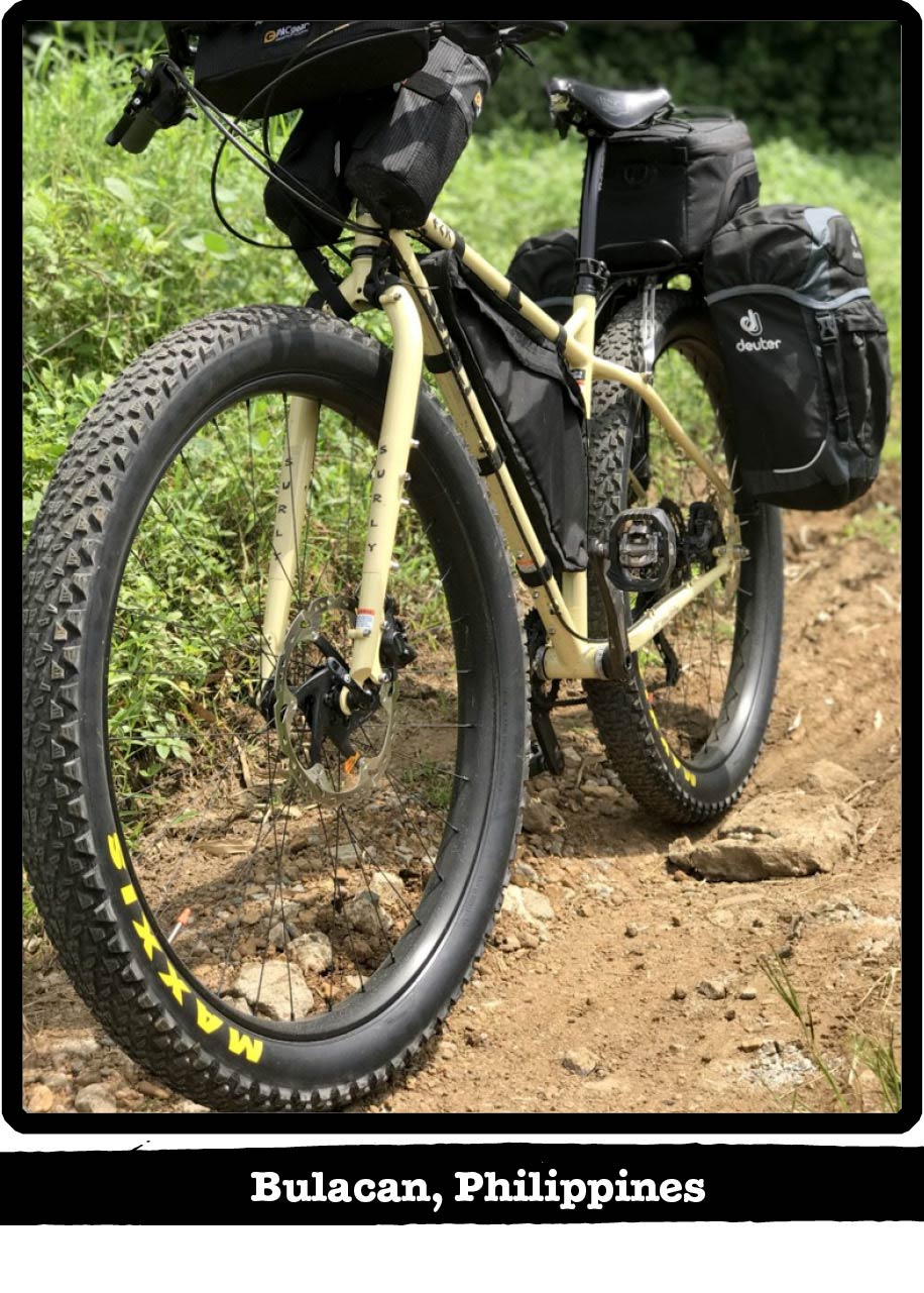 Front view of a tan Surly bike on a rocky dirt trail with weeds behind-Bulacan, Philippines banner below image
