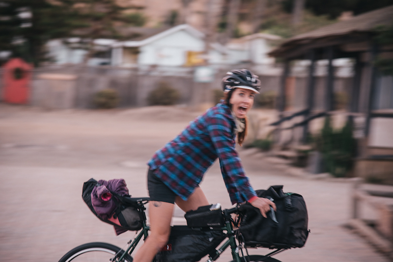 Right side, blurry view, of a cyclist on a bike, looking to the right side with their mouth wide open