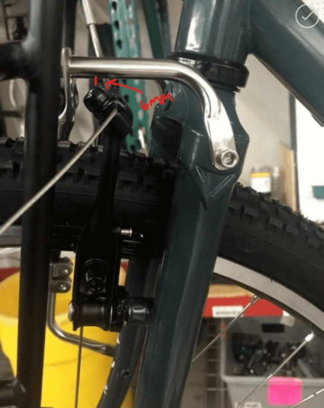Close up left side view of the fork of a Surly Cross Check bike with Pack Rack, with an arrow pointing to a brake noodle