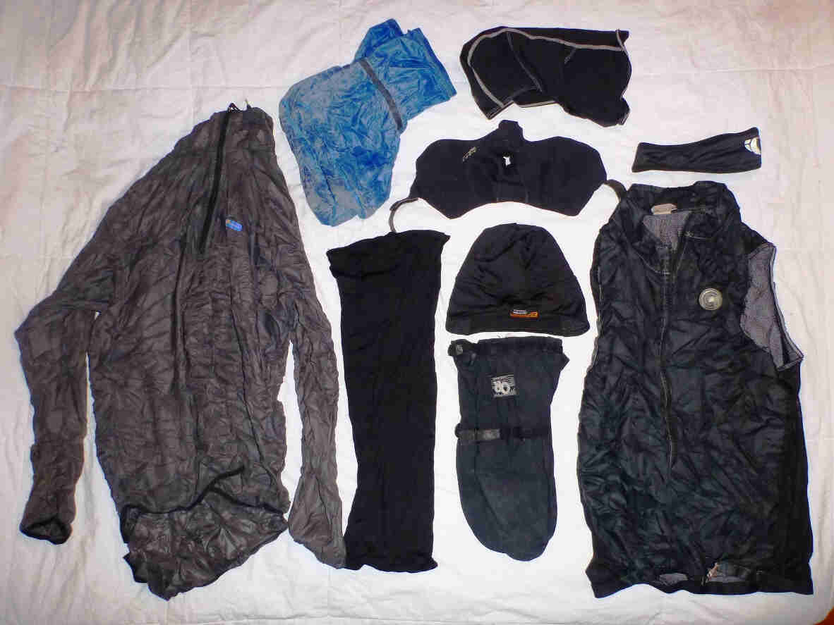 Downward, view of cold weather clothing items, laid out on a white blanket