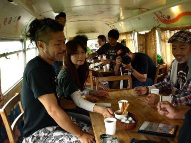 People sitting around a table, inside of a double decker bus that's been converted into a diner and cafe