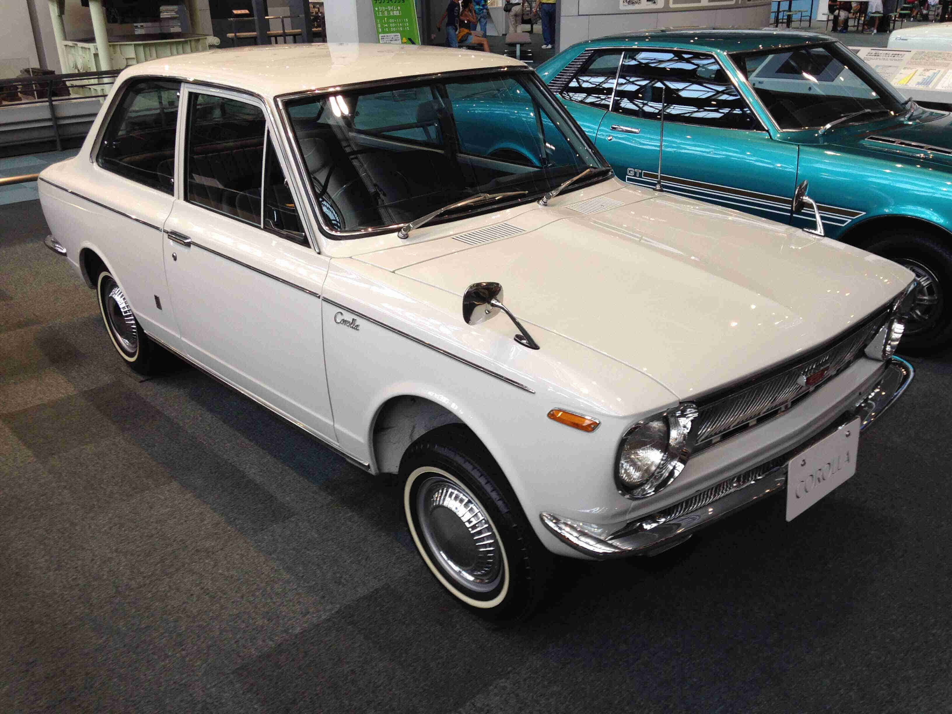 Front, right side view of a white, 1970s style Toyota Corolla, in a parking garage