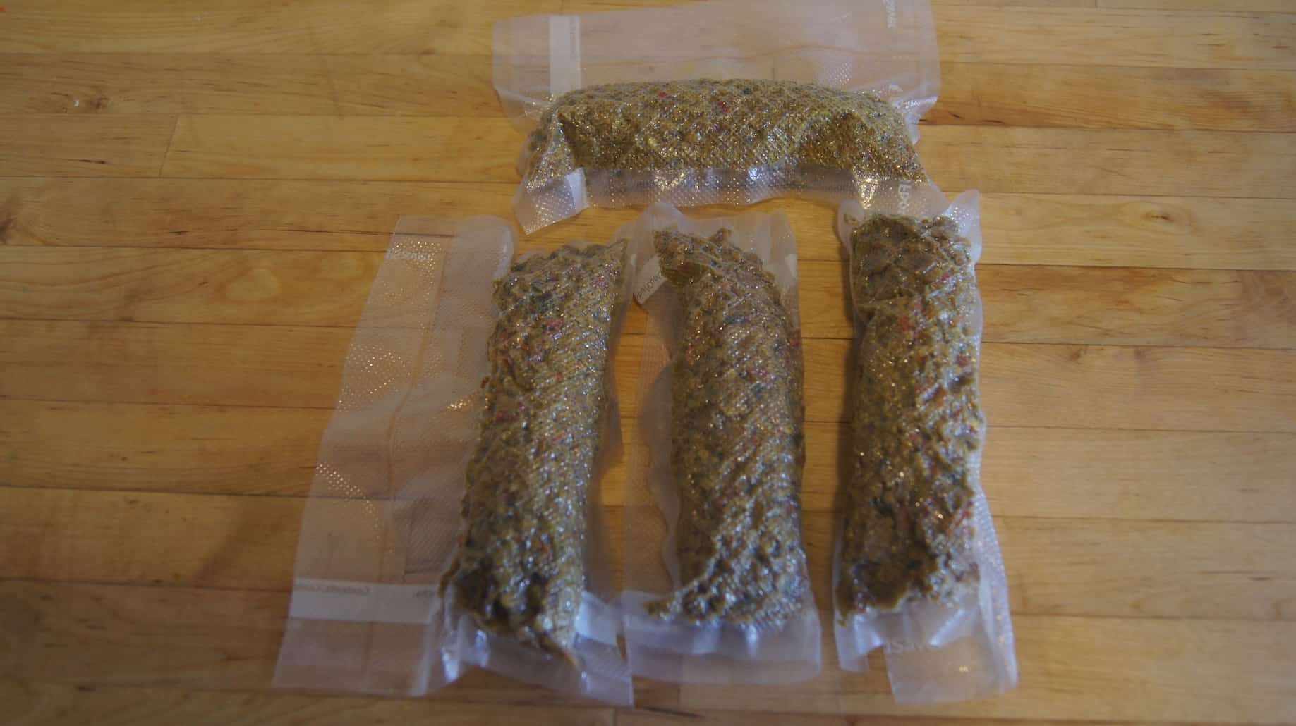 Downward view of four vacuum sealed bags of soup ingredients, on top of a wood countertop