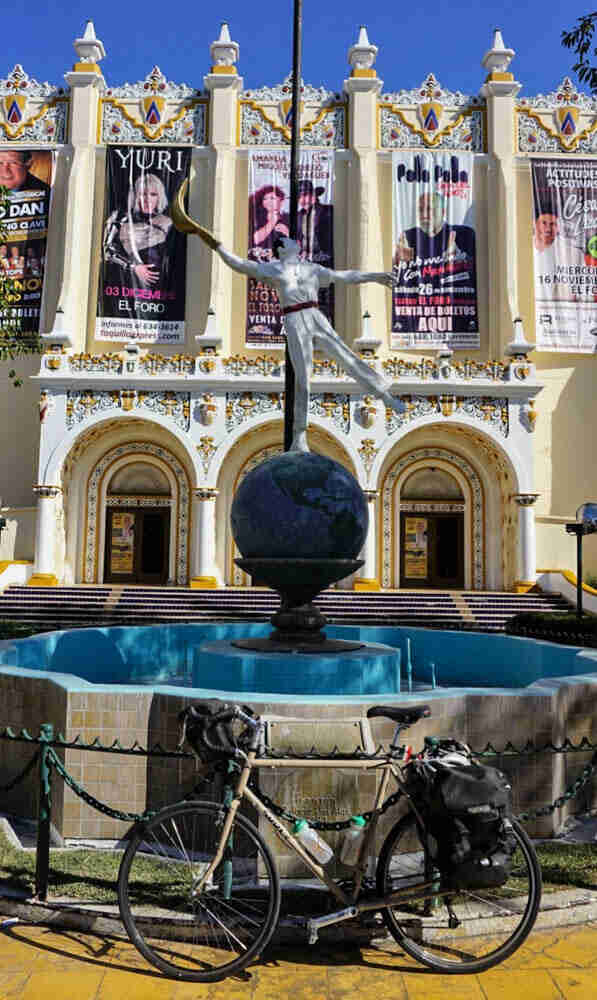 Left profile of a Surly bike in front of a courtyard fountain, with a decorative building in the background