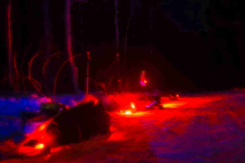 Red saturation of a snowy road with lights and gear on the side, in the woods at night
