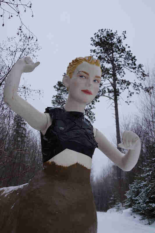 Front, close up view of a figure, with a mannequin upper half, and an animal lower half, in the snowy woods 